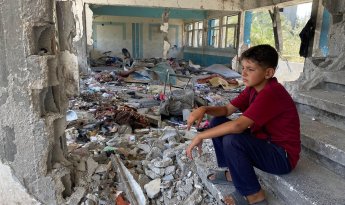 Boy sitting in the rubble of a destroyed UNRWA school in Nuseirat, Middle Areas. © 2024 UNRWA Photo